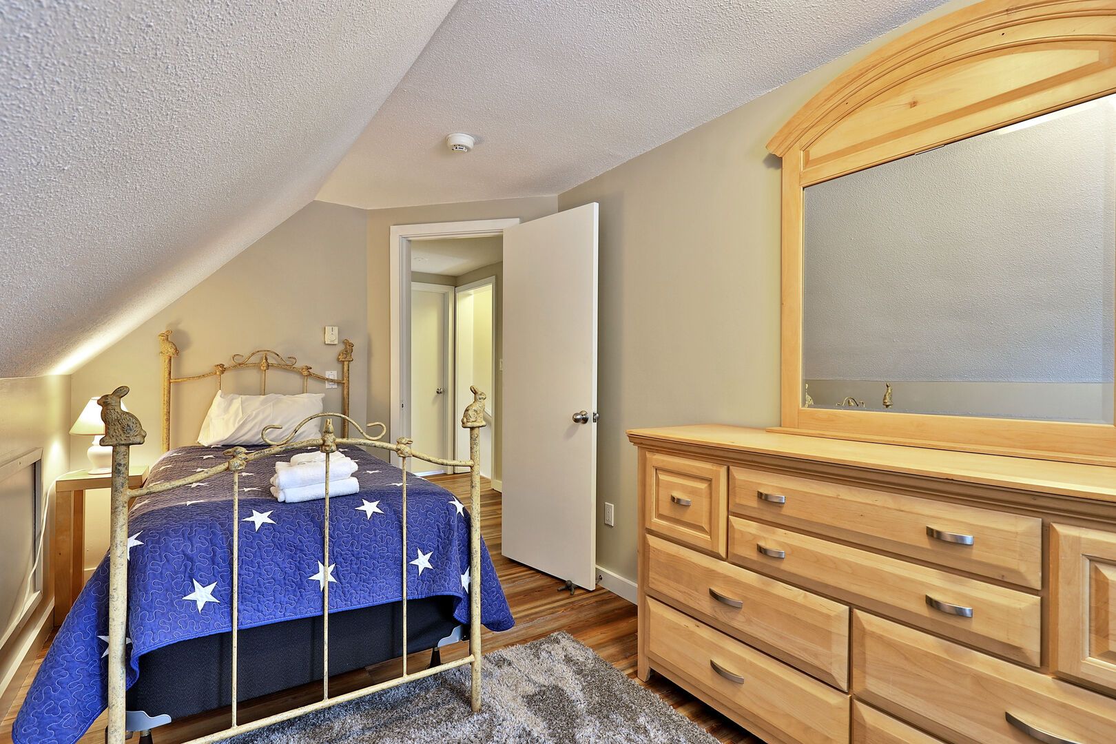 Un dormitorio con cama, cómoda de madera y espejo.