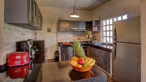 A kitchen with a stone wall, a wooden countertop, a red toaster, a bowl of fruit, and a refrigerator. - Comfortable apartment only 3 blocks from 5th av (Playa del carmen)