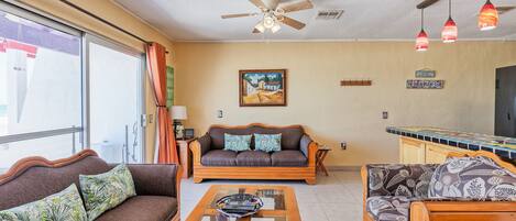 A living room with a sofa, a coffee table, and a ceiling fan.