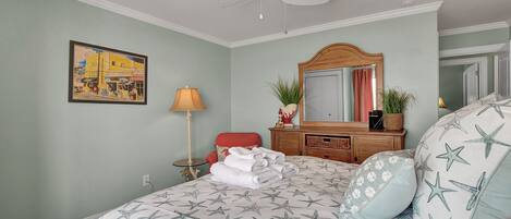 A bedroom with a bed, a dresser, a mirror, a lamp, and a painting on the wall.