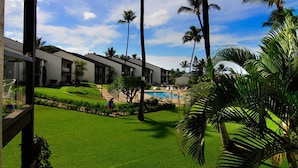 Un hotel con edificios de varios pisos, una piscina y exuberante vegetación, incluyendo palmeras.