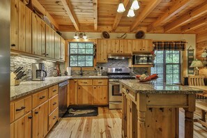 A kitchen with wooden cabinets, granite countertops, a stainless steel refrigerator, and a built-in oven. - PICK'S RIVERSIDE RETREAT - 2 Bedroom plus Loft Riverside Retreat on the Upper Toccoa River (Blue Ridge)