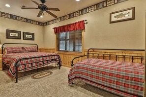 A room with two beds, a ceiling fan, a window with blinds, and framed fish pictures on the wall. - PICK'S RIVERSIDE RETREAT - 2 Bedroom plus Loft Riverside Retreat on the Upper Toccoa River (Blue Ridge)