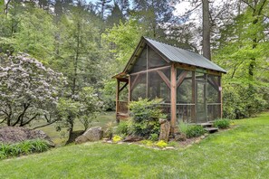 A wooden gazebo with a metal roof, surrounded by lush greenery and a pond. - PICK'S RIVERSIDE RETREAT - 2 Bedroom plus Loft Riverside Retreat on the Upper Toccoa River (Blue Ridge)