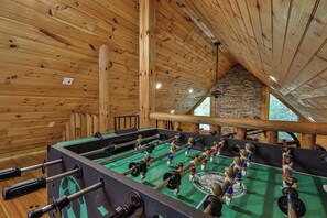 A wooden-floored room with a foosball table and a stone wall. - PICK'S RIVERSIDE RETREAT - 2 Bedroom plus Loft Riverside Retreat on the Upper Toccoa River (Blue Ridge)