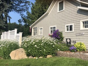 A house with a well-maintained garden, a white picket fence, and a sign that reads "The Cottage."