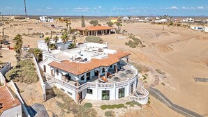 Une grande maison à deux étages, avec un toit recouvert de tuiles rouges, plusieurs balcons et un patio.