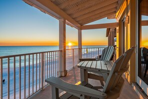 A covered outdoor area with a view of the sunset over the ocean, featuring a table and chairs. - *Toes in the Sand*Elevator*Beach Service*Private Beach* (Miramar Beach)