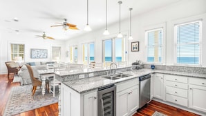 A spacious kitchen with a granite countertop, white cabinetry, and a built-in dishwasher.