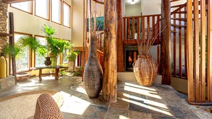 Eine geräumige Lobby mit großen Fenstern, einer Steinsäule und einer Holztreppe.