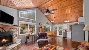 A spacious living room with a stone fireplace, leather armchair, and a large television. - 2 Master Suites - Hot Tub - Porch - Fire Pit - Wi-Fi - Clean - Cozy - 5 Stars! (Maggie Valley)