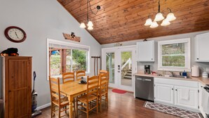 A kitchen with wooden cabinets, a dining table with chairs, a clock, and a ceiling light fixture. - 2 Master Suites - Hot Tub - Porch - Fire Pit - Wi-Fi - Clean - Cozy - 5 Stars! (Maggie Valley)
