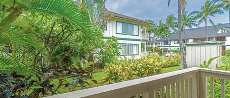 A hotel with a white exterior, green trim, and a balcony with a wooden railing.