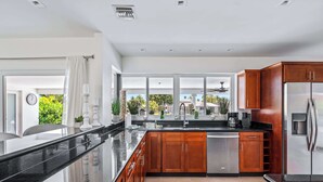 A modern kitchen with a large island, stainless steel appliances, and wooden cabinets.