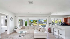 A modern living room with a sectional sofa, a glass coffee table, and a view of the outdoors.