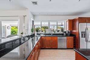 Una cocina moderna con una isla grande, electrodomésticos de acero inoxidable y armarios de madera.