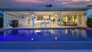 A modern house with a swimming pool, a dining area, and a kitchen.