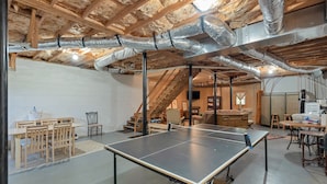 Une pièce spacieuse avec une table de ping-pong, des meubles en bois et des poutres apparentes.