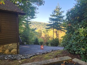 A cabin with a stone foundation, surrounded by a forested area with a clear sky.