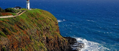 A lighthouse on a cliff overlooking the ocean with waves crashing against the rocks below.