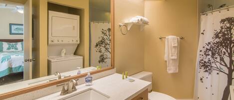 A bathroom with a sink, mirror, toilet, and shower curtain.