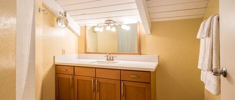 A bathroom with wooden cabinets, a sink, a mirror, and a towel rack.