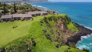 Ein Küstenhotel mit mehreren Gebäuden, einem gepflegten Rasen und Blick auf das Meer und die Berge.
