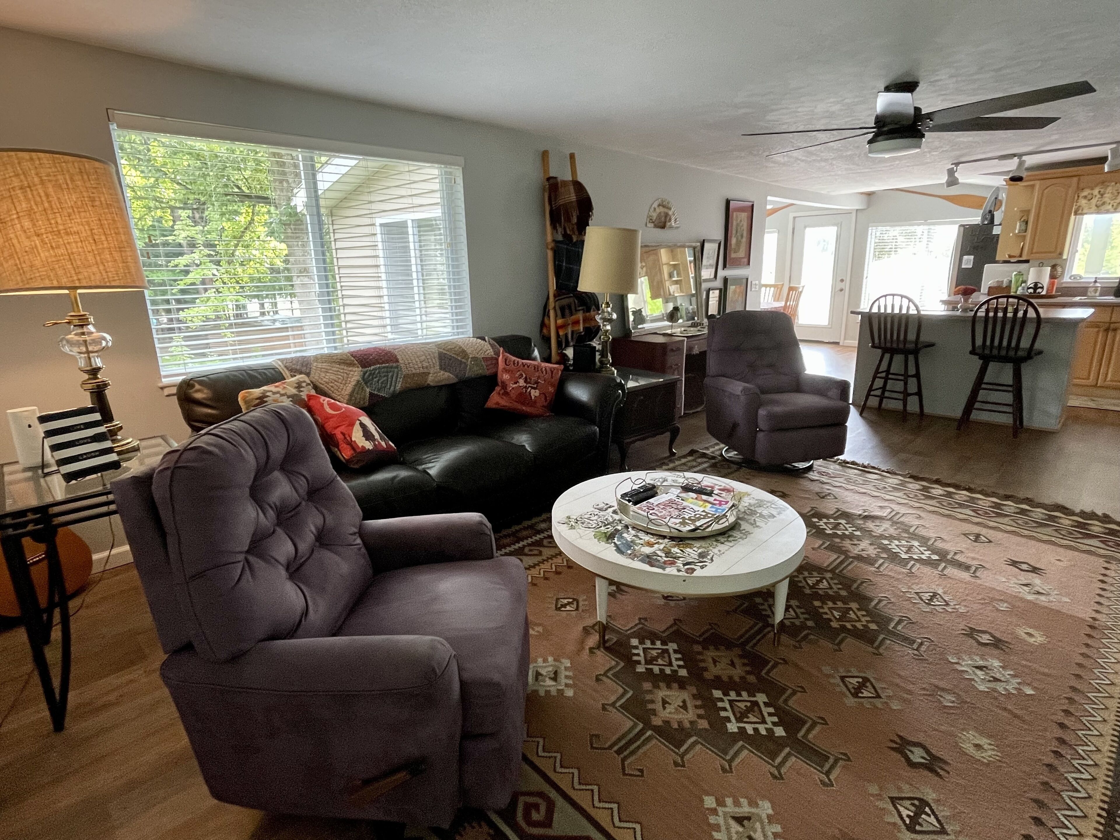 A living room with a sofa, armchair, coffee table, and a patterned rug.