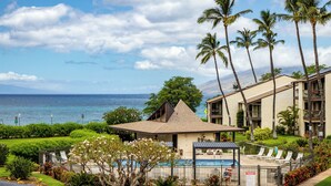 A resort with a pool, palm trees, and a view of the ocean.