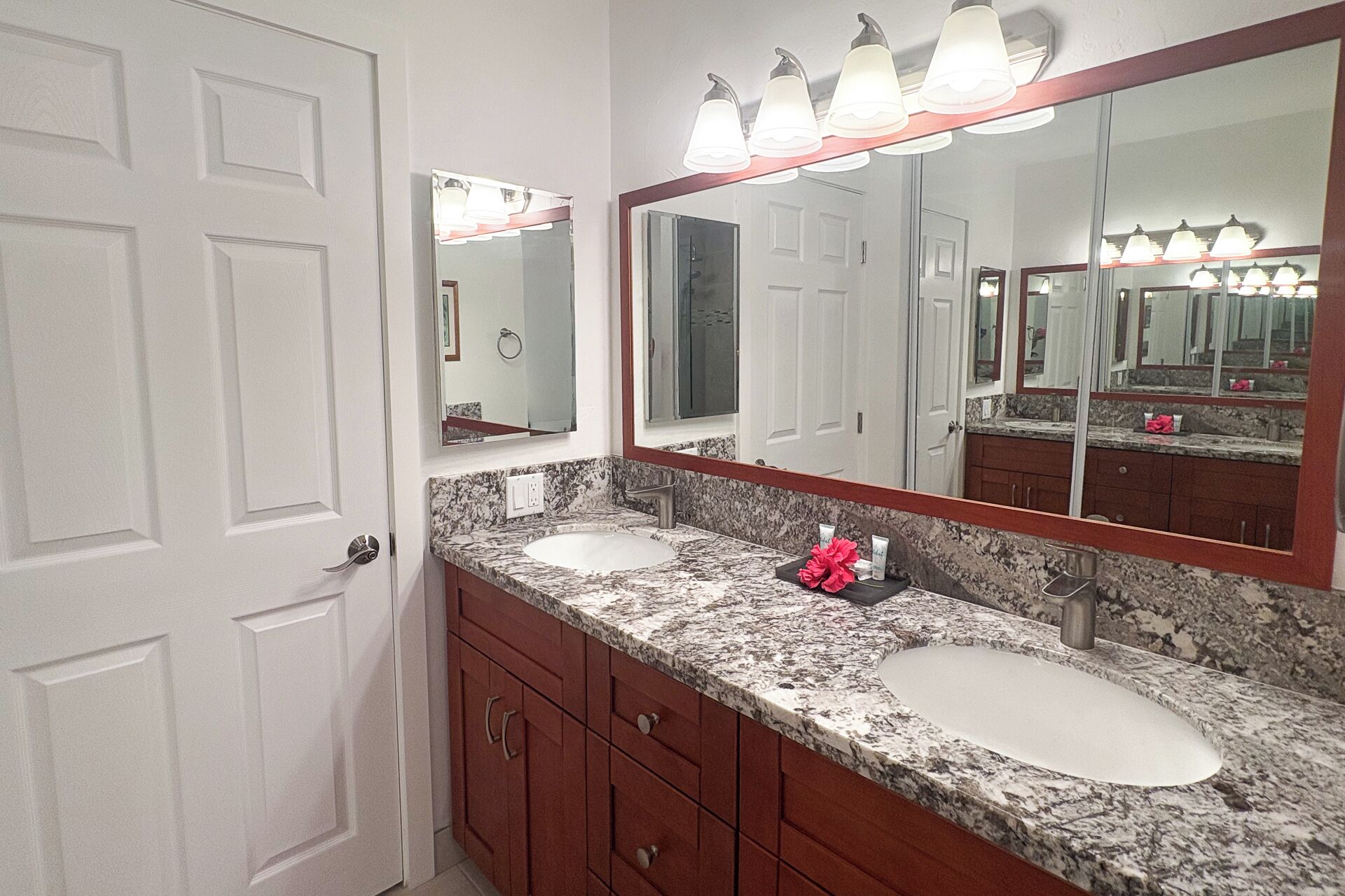 A bathroom with two sinks, a large mirror, and a door.