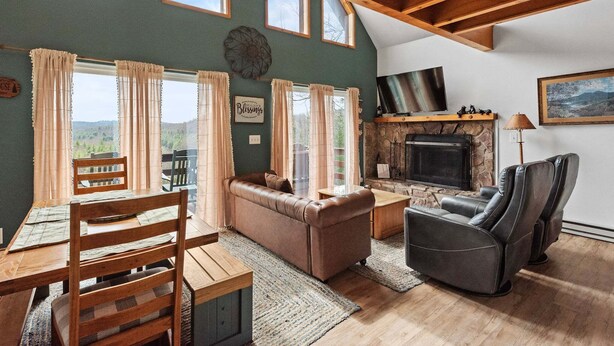 A cozy living room with a fireplace, leather sofa, and a dining area with wooden furniture.