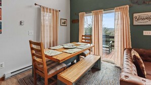 A dining area with a wooden table, benches, and a view through a glass door to an outdoor patio.