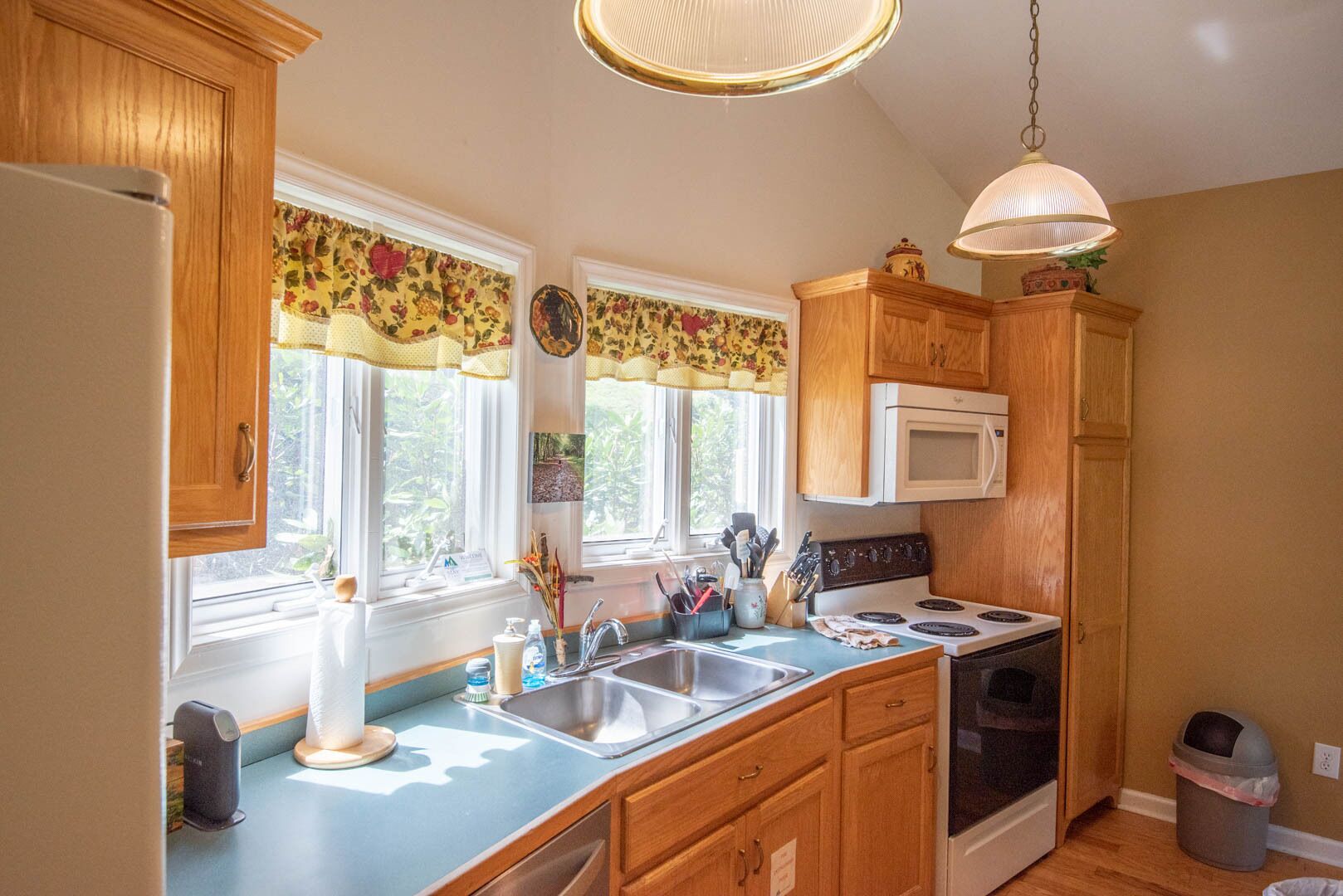 A kitchen with wooden cabinets, a white stove, a microwave, and a sink.