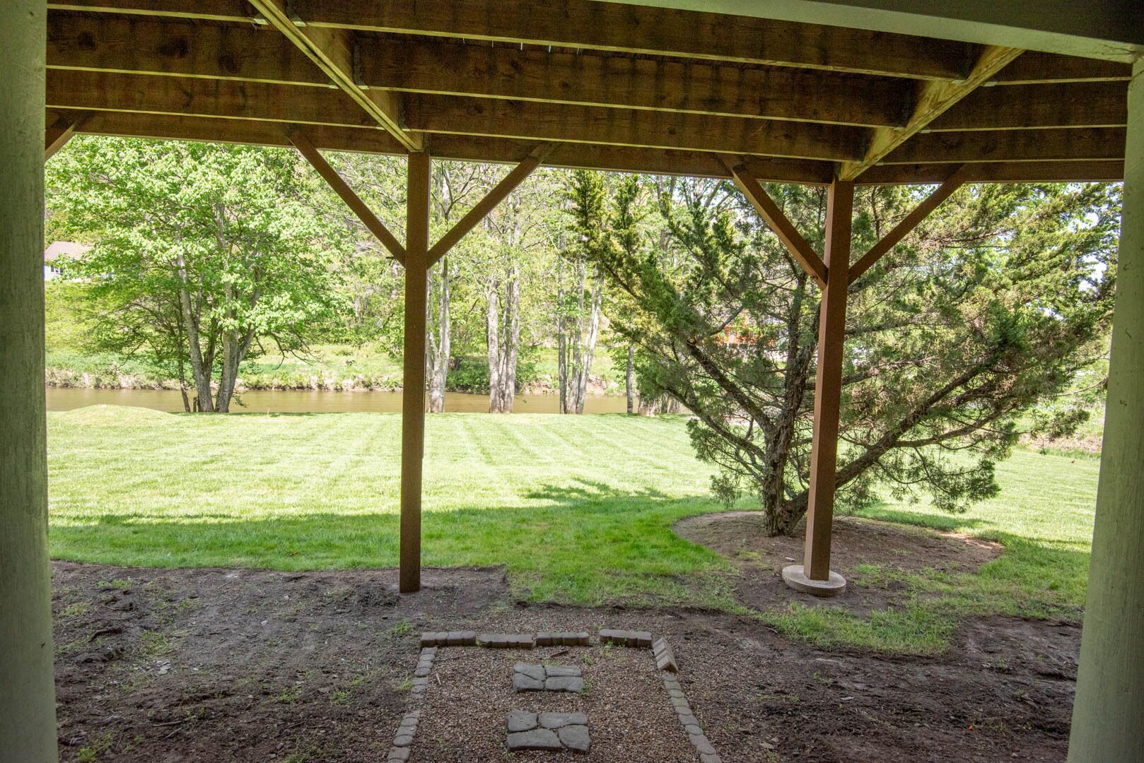 Un espace extérieur abrité, doté d’une structure en bois, d’une pelouse et d’arbres.