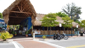 A restaurant with a thatched roof, outdoor seating, and a blue facade. - Affordable Ground Floor Siesta Key Vacation Rental with Heated Pool Access (Sarasota)