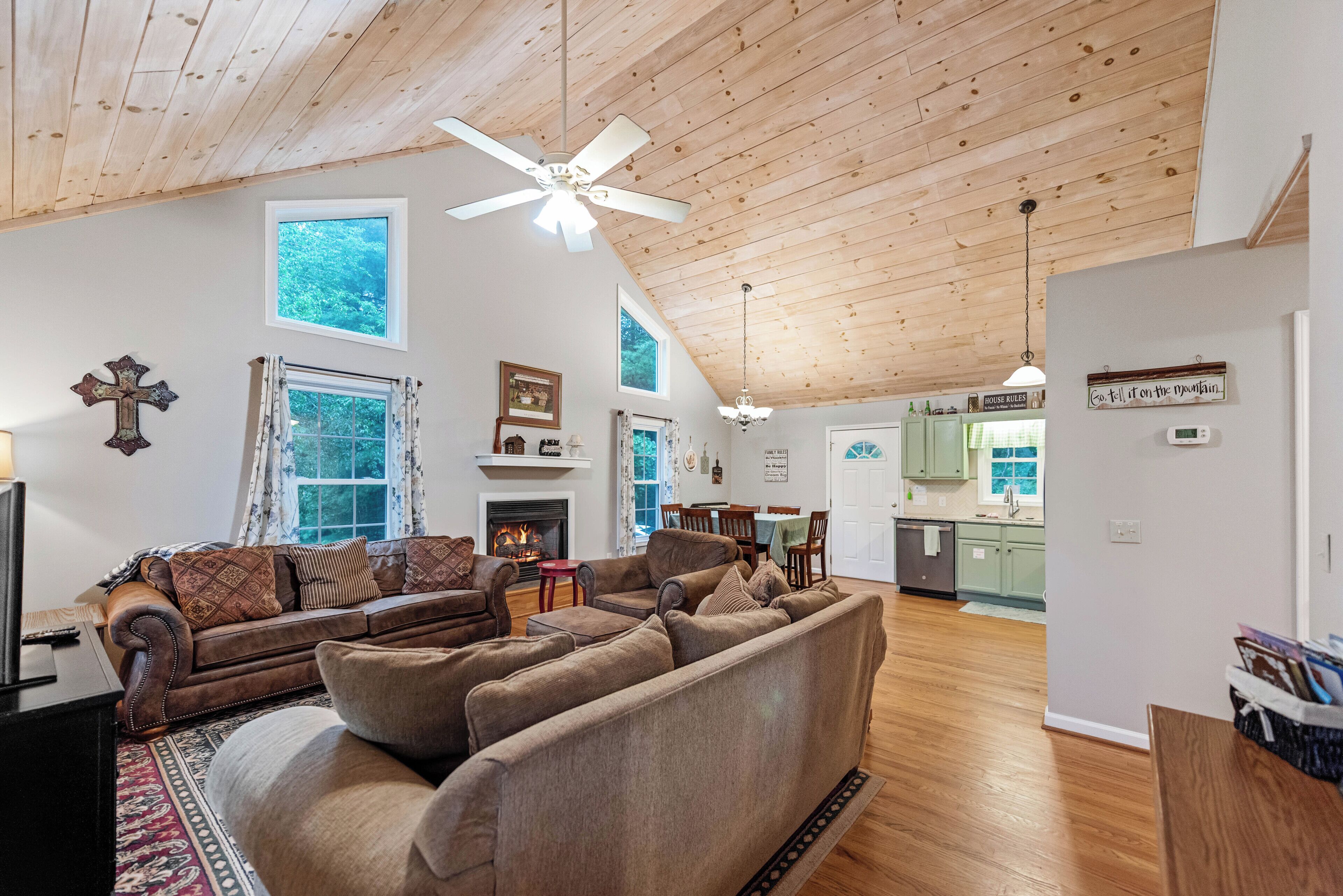 A spacious living room with a fireplace, a dining area, and a kitchen with green cabinets.