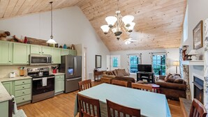 Une cuisine spacieuse équipée d’appareils électroménagers modernes, un coin repas avec une table et des chaises, et un salon avec un canapé et une télévision.