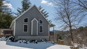 Une maison à deux étages avec un toit à pignon, un porche à l’avant et une terrasse.