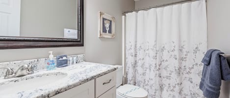 A bathroom with a marble sink, a toilet, and a shower curtain.