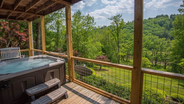 Un bain à remous sur une terrasse en bois, avec vue sur un paysage verdoyant et luxuriant.