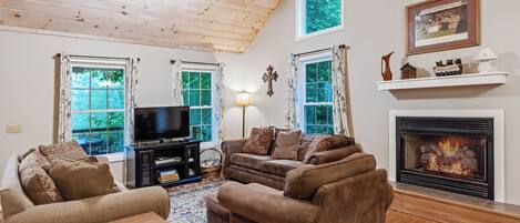 A living room with a fireplace, a television, and a ceiling fan.