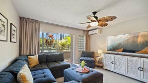 A modern living room with a sectional sofa, ottoman, and a flat-screen TV.