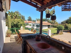 A patio with a stone sink, wooden table, and chairs. - Beautiful villa/farmhouse in exclusive 5,000m2 botanical garden, private pool (La Orotava)