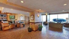 Un hall con mostrador de recepción, zona de estar y ventanas amplias.
