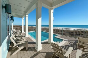 Un espace extérieur abrité avec une piscine, des chaises longues et une vue sur la plage.