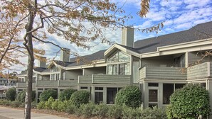 A row of townhouses with multiple balconies, a covered front porch, and a well-maintained garden.