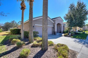 A residential house with a garage, surrounded by palm trees and well-maintained landscaping.