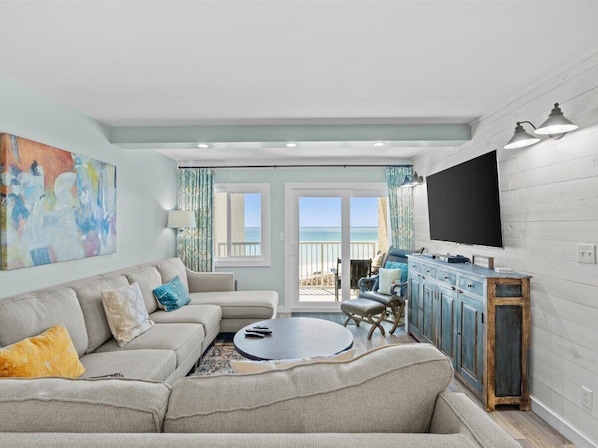 A living room with a sofa, coffee table, and a TV mounted on the wall.