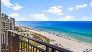Een hotel aan het strand met een balkon en uitzicht op zee en strand.