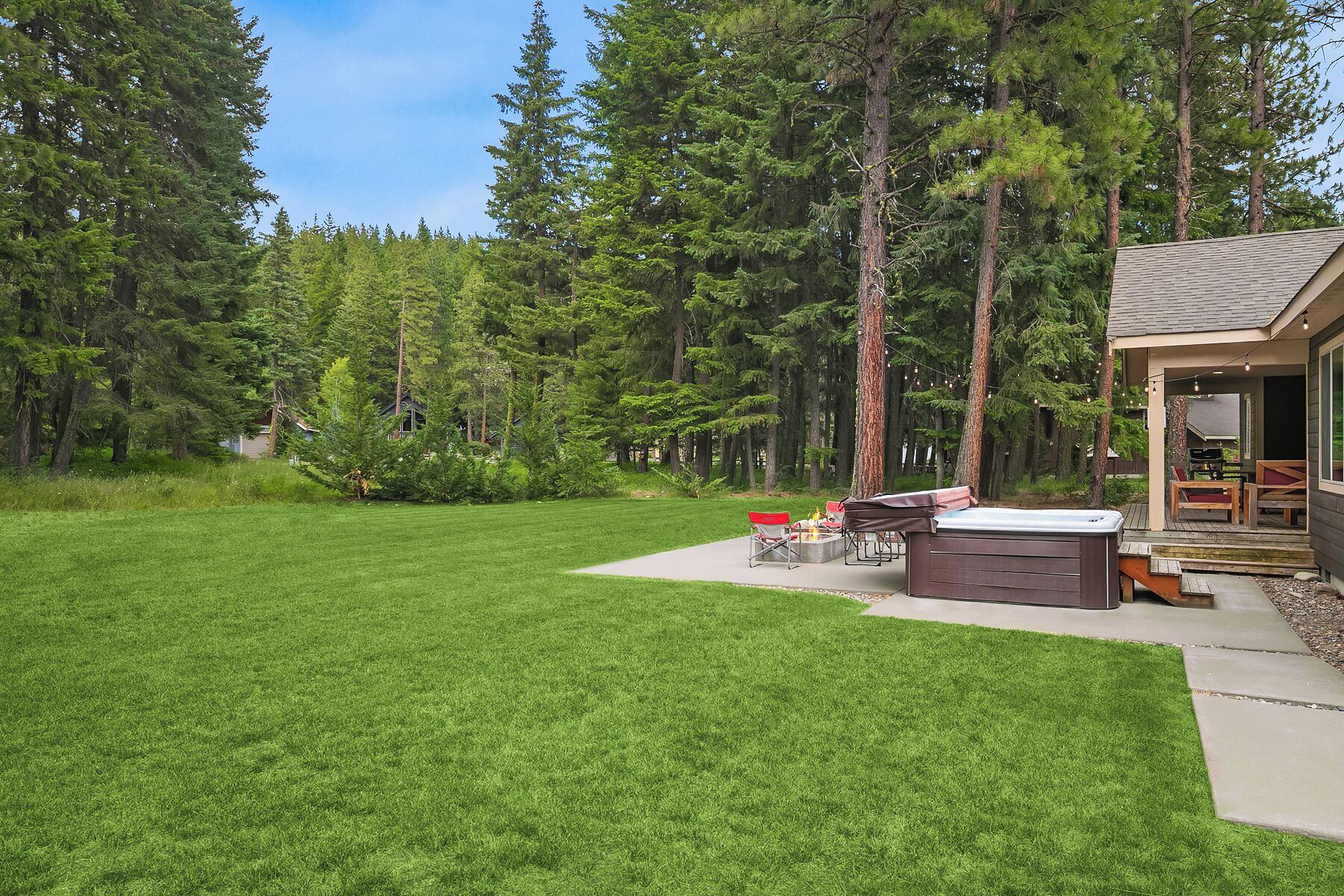 A well-maintained backyard with a hot tub, outdoor seating, and a deck area.